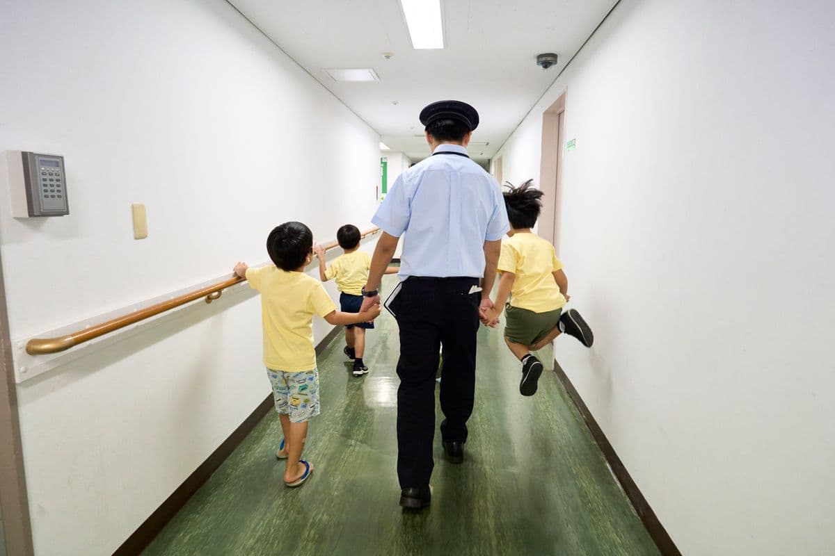 駅員さんと手をつないで歩く子どもたち
