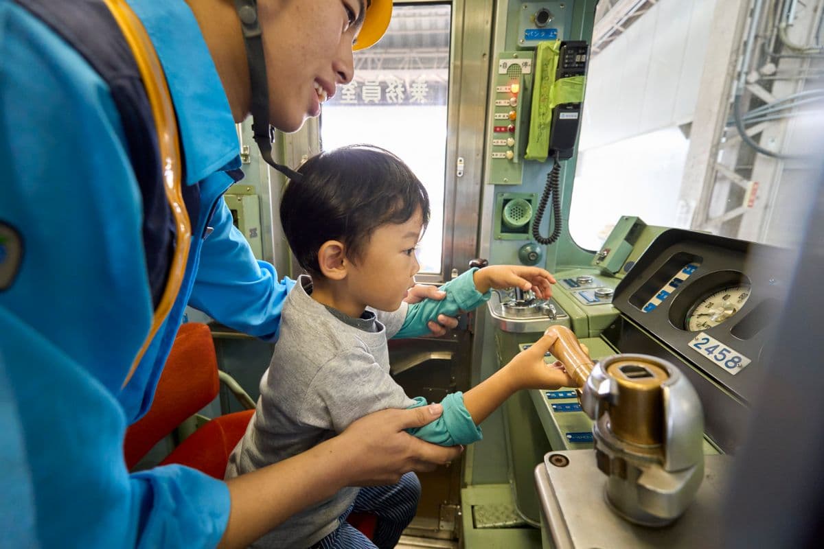 運転台で機器を操作する子ども