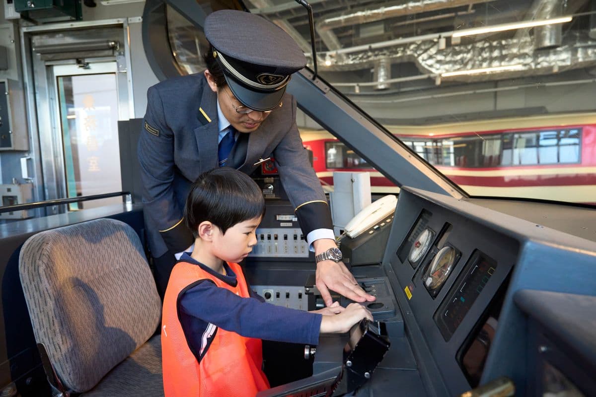 駅員さんと一緒に運転台を操作する子ども